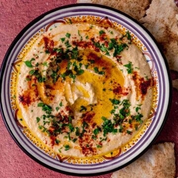 Easy and creamy homemade hummus is garnished with olive oil and sprinkle of paprika on top.
